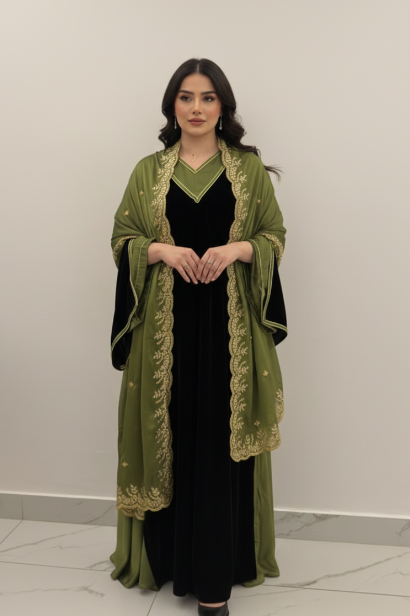 Woman wearing a green embroidered abaya over a black dress against a white background